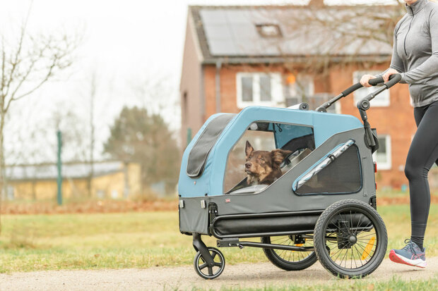 Trixie joggingkit uitbreidingsset met zwenkbaar voorwiel en duwarm gemonteerd op de blauw-grijze hondenfietskar.
